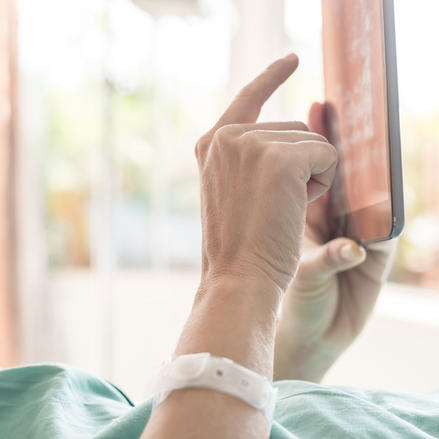 Patient im Krankenzimmer bedient ein Tablet